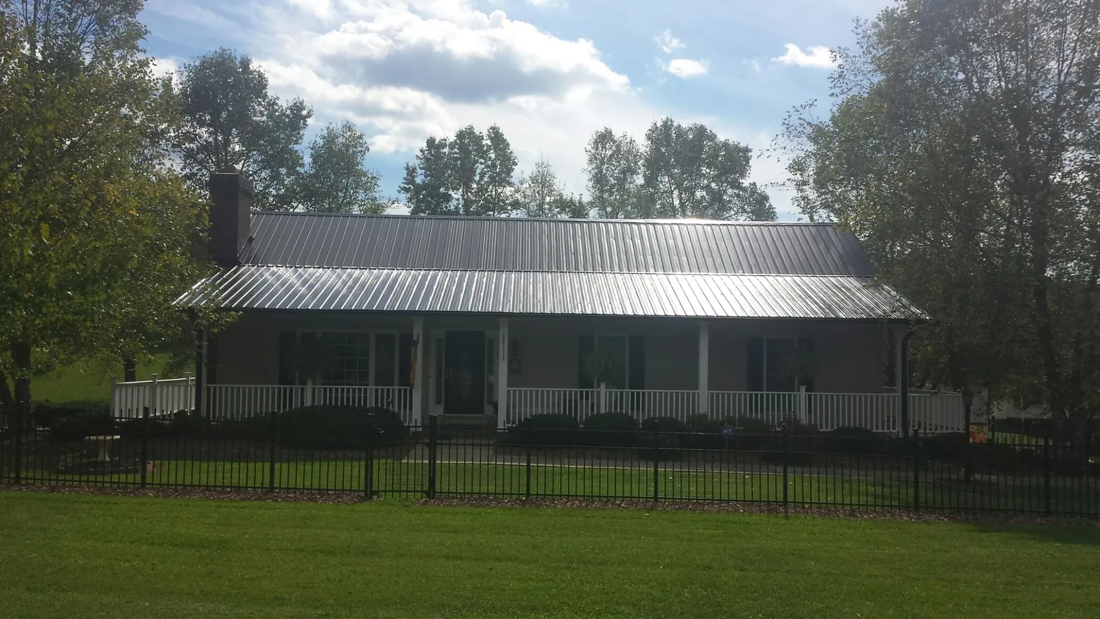 Gray metal roof on a brick ranch with a full width front porch — Gutter Guard Installation work by our crew in Medina